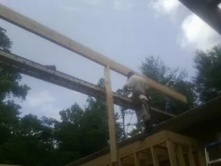 Carpenter setting a ridge beam over a new addition frame — Ice Dam Removal by Roofing Brothers in Big Run