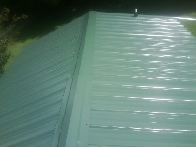 New green metal panels meeting at the ridge of a roof — Flat Roof Repair work by our crew in Big Run