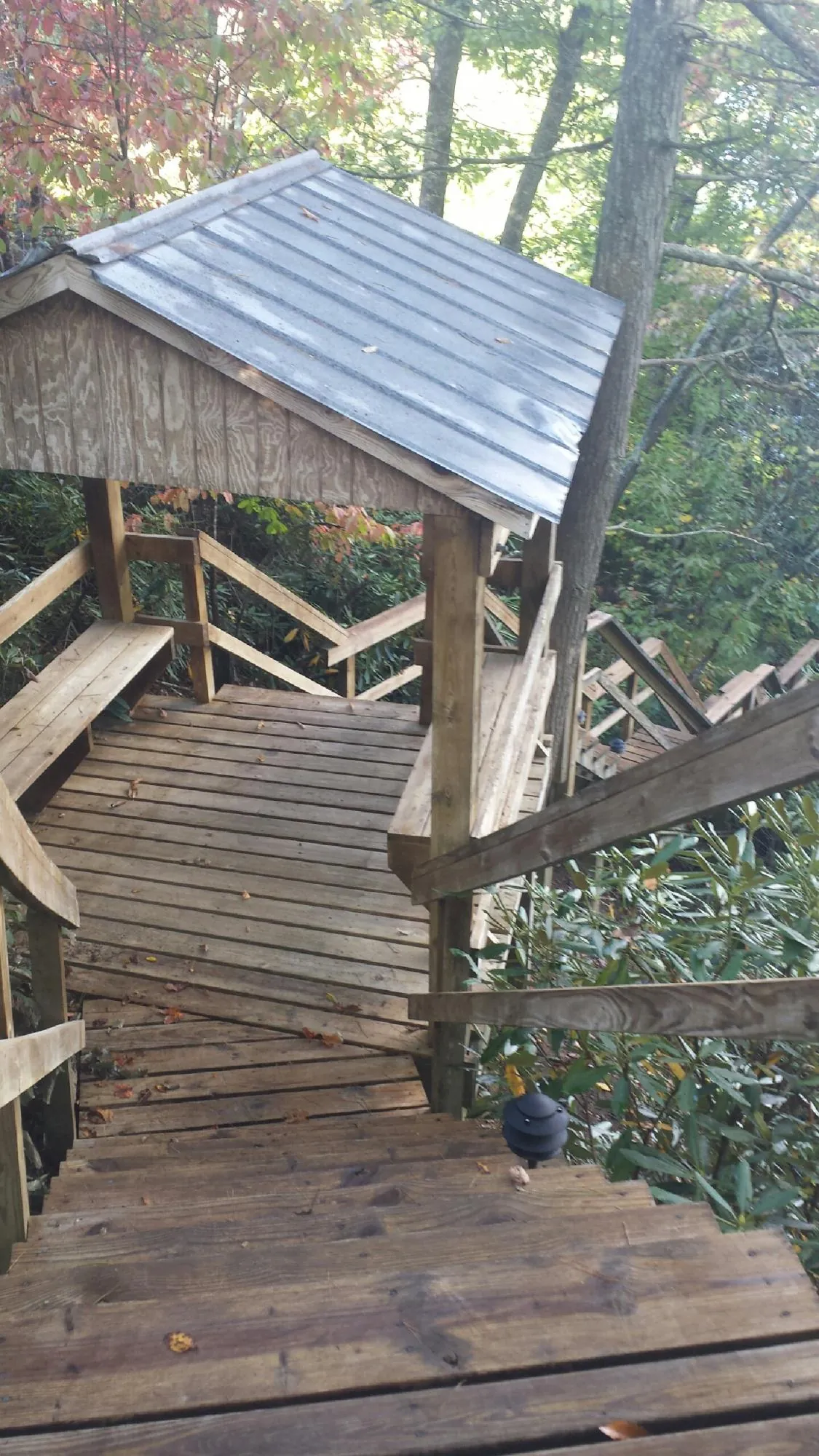Metal roofed shelter over wooden steps on a wooded walkway — Skylight Repair & Installation work by our crew in Big Run