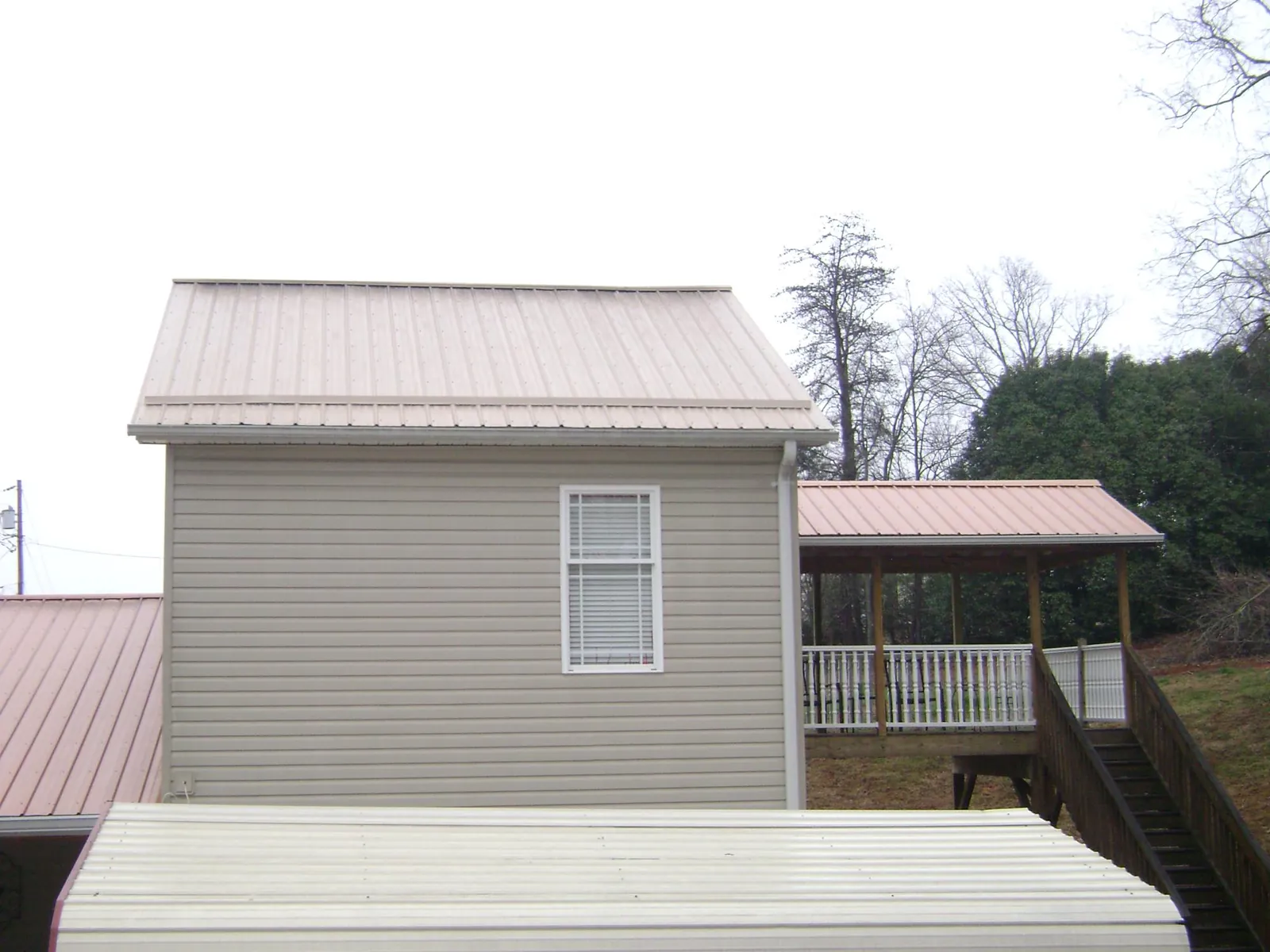 Tan metal roofs on a two story addition and attached porch, from a Roof Replacement job in Big Run